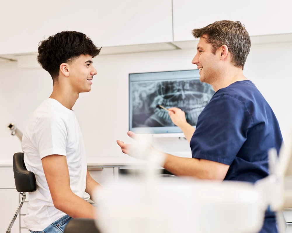 Dr. Kalkreuter klärt Patient zur Weisheitszahnentfernung am Monitor auf.