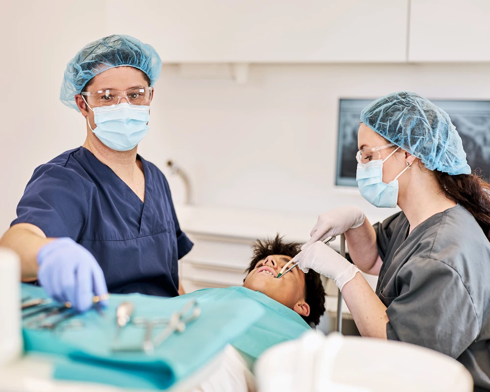 Patient in Behandlung. Dr. Kalkreuter und Assistenz behandeln Patienten.